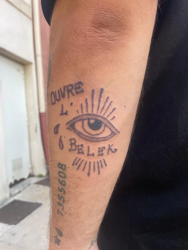 Œil rayonnant et les mots « Ouvre l'œil, belek », sur un avant-bras